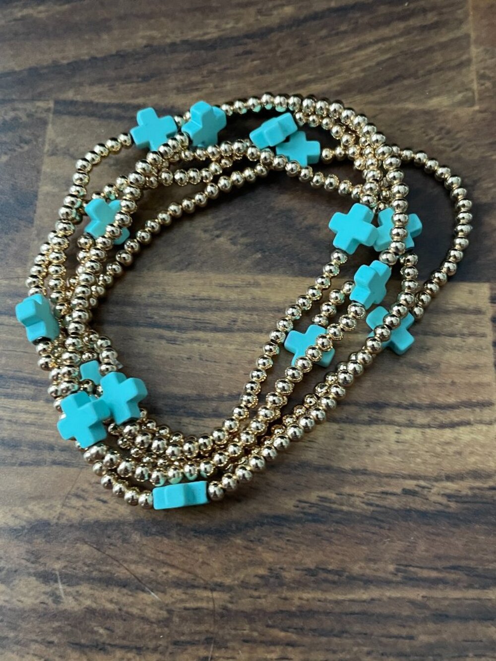 gold-tone beaded stretch bracelets decorated with turquoise-colored cross charm